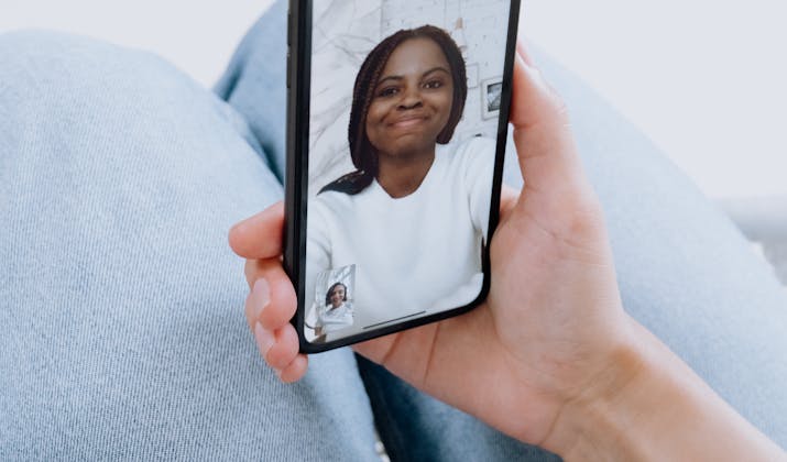 How To Get Facetime Back To Full Screen 2 Hand holding phone on video call, smiling woman.