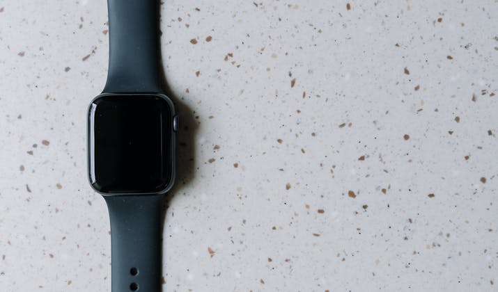 Apple Watch Black Screen - Troubleshooting Tips 4 Black Apple Watch with silicone band placed on a speckled countertop.