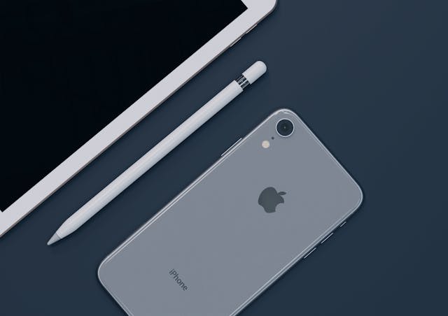 How To Find Hidden Messages On iPhone 2 Flat lay of space gray iPhone, iPad and Apple Pencil on dark desk