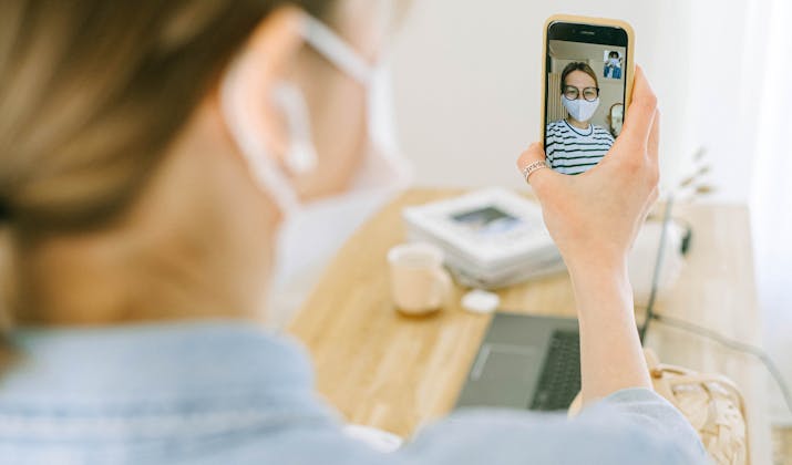 How To Get Facetime Back To Full Screen 1 Woman video calling with mask at a desk.