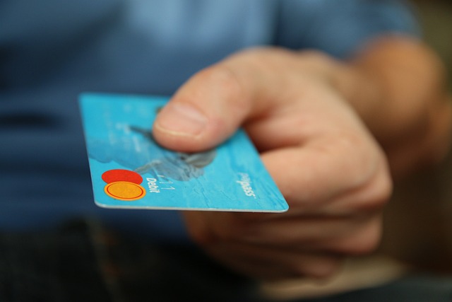 Apple Pay Pending - Explained 2 Close-up of hand holding a blue debit card online payment and credit card purchase.