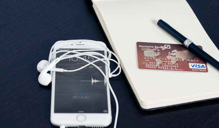 How to Dispute Apple Charges 1 iPhone with wired earbuds beside Visa credit card on notebook