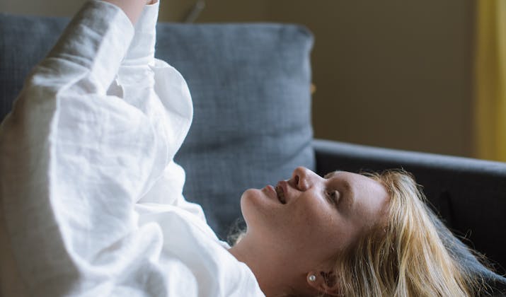 How To Get Facetime Back To Full Screen 3 Woman lying on couch looking at smartphone.