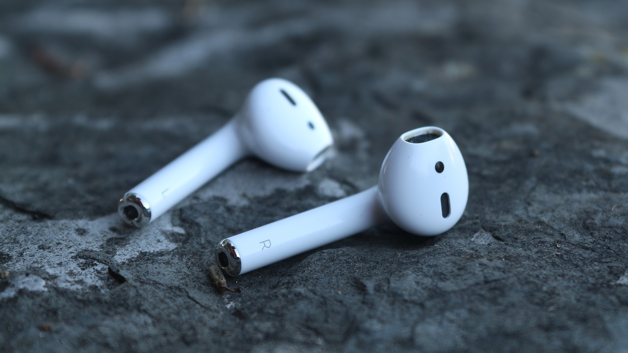 Airpods Connection Rejected - Troubleshooting Tips 1 Close-up of Apple AirPods wireless earbuds placed on a rough stone surface, showing left and right earpieces