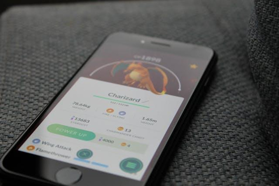 Pokémon GO Charizard stats and Power Up screen displayed on a phone
