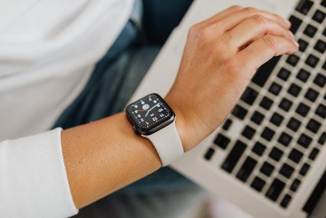 How to Resize Your Apple Watch Screen 1 A person glancing on their Apple Watch with a MacBook in the background