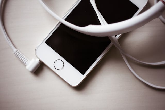 An iphone with earbuds plugged into the 3.5 mm  jack.