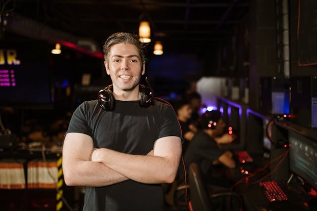 a gamer standing in a gaming arcade with headset resting on shoulders.