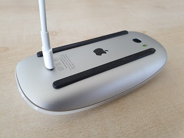 An upside down magic mouse being charged.