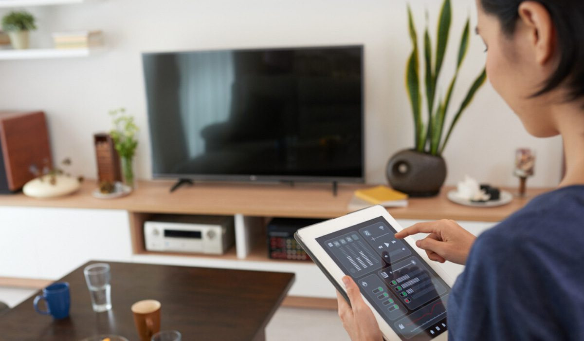 Smart Home Technology: The Definitive Guide 8 A woman using a touch pad device to control her home.