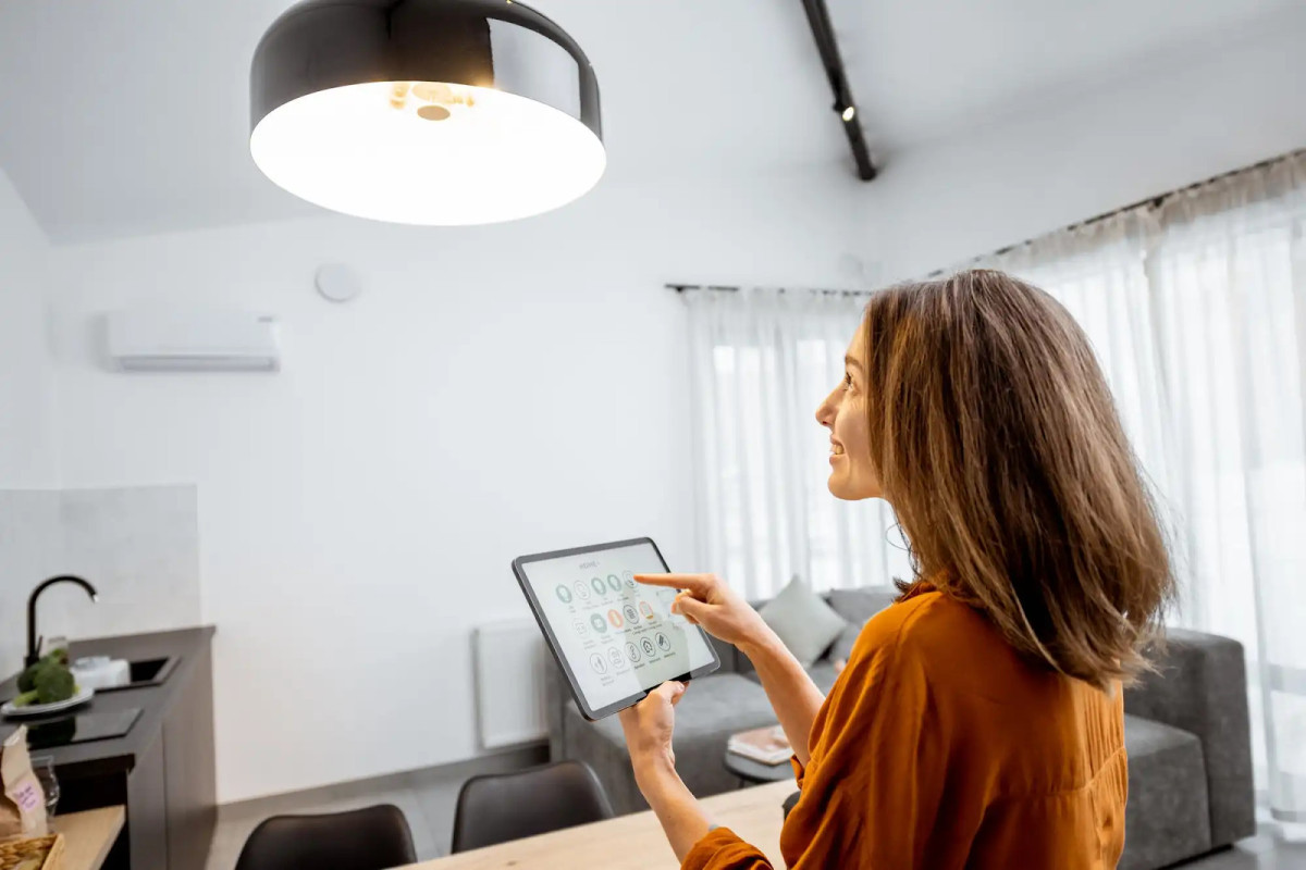Smart Home Technology: The Definitive Guide 5 A woman using a touch pad device to control her home lighting.