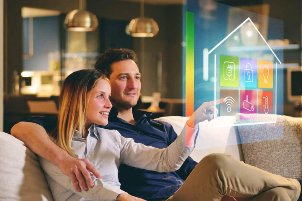 Smart Home Technology: The Definitive Guide 19 A couple sitting on the couch seemingly touching a hologram.