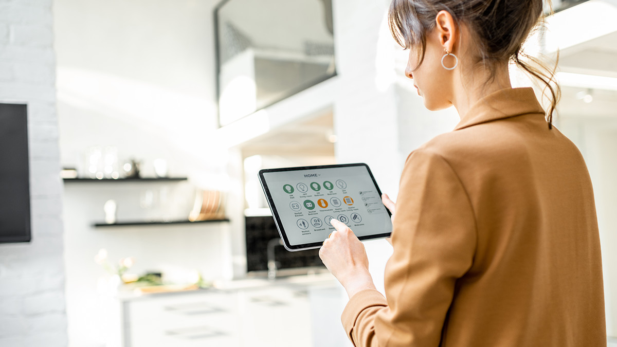 Smart Home Technology: The Definitive Guide 2 A woman using a touch pad device to control her home.