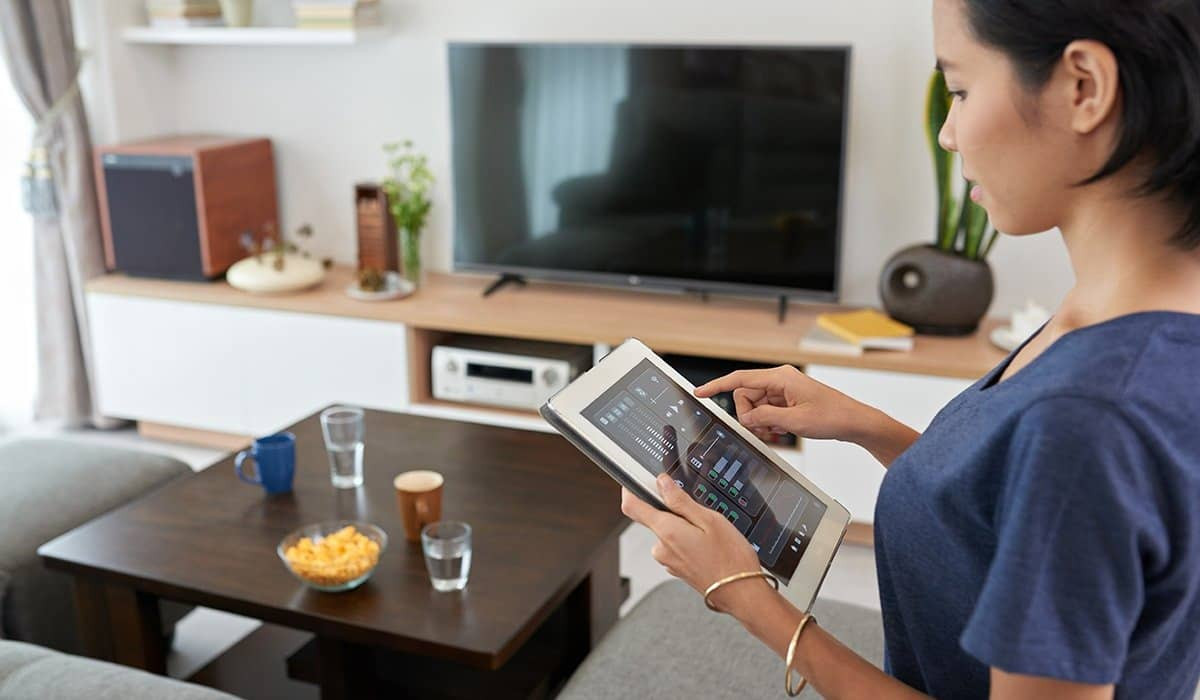 Smart Home Technology: The Definitive Guide 3 A woman using a touch pad device to control her home.